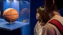 Pengunjung melihat bola basket bertanda tangan pendatang baru terbaik Ben Simmons dalam pameran NBA (National Basketball Association) di Beijing, China, Senin (19/8/2019). (NICOLAS ASFOURI/AFP)