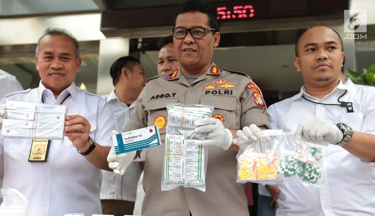 Kabid Humas Polda Metro Jaya Kombes Argo Yuwono dan Kasubdit Indag AKBP Sutarmo memperlihatkan barang bukti obat keras dalam ungkap kasus di Jakarta, Selasa (19/9). Polisi menyita 15.367 pil obat daftar G yang tidak terdaftar. (Liputan6.com/Faizal Fanani)