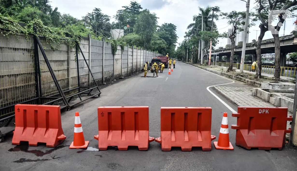 Pekerja Suku Dinas Bina Marga Jakarta Utara menyelesaikan perbaikan jalan jelang gelaran balap liar legal di Jalan Inspeksi Kali Ancol, Pademangan, Rabu (12/1/2022). Polda Metro Jaya resmi menjadikan Jalan Inspeksi Kali Ancol sebagai arena balap liar legal. (merdeka.com/Iqbal S. Nugroho)