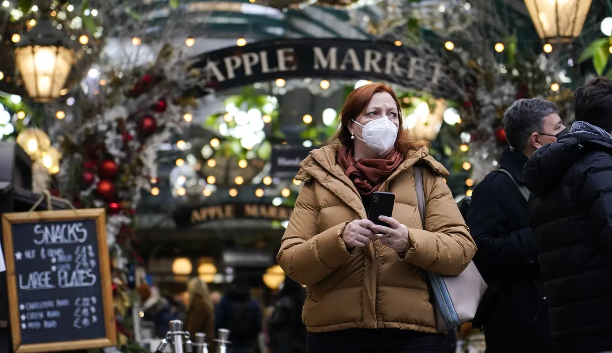 Seorang wanita memakai masker saat dia berjalan di pasar Covent Garden, di London, Kamis (16/12/2021). Inggris mencatat jumlah tertinggi infeksi COVID-19 baru yang dikonfirmasi pada hari Rabu (15/12) sejak pandemi dimulai. (AP Photo/Alberto Pezzali)
