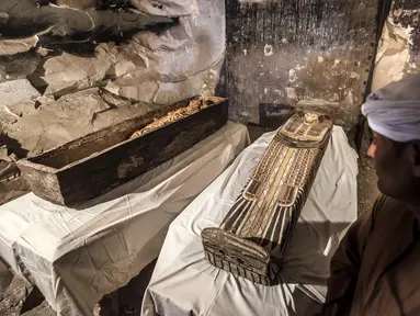 Pekerja Mesir berdiri dekat mumi wanita bernama Thuya dalam sarkofagus yang baru dibuka di Kota Luxor, Sabtu (24/11). Mumi itu diawetkan dengan baik di dalam sarkofagus yang belum pernah dibuka sejak lebih dari 3.000 tahun lalu. (Khaled DESOUKI/AFP)