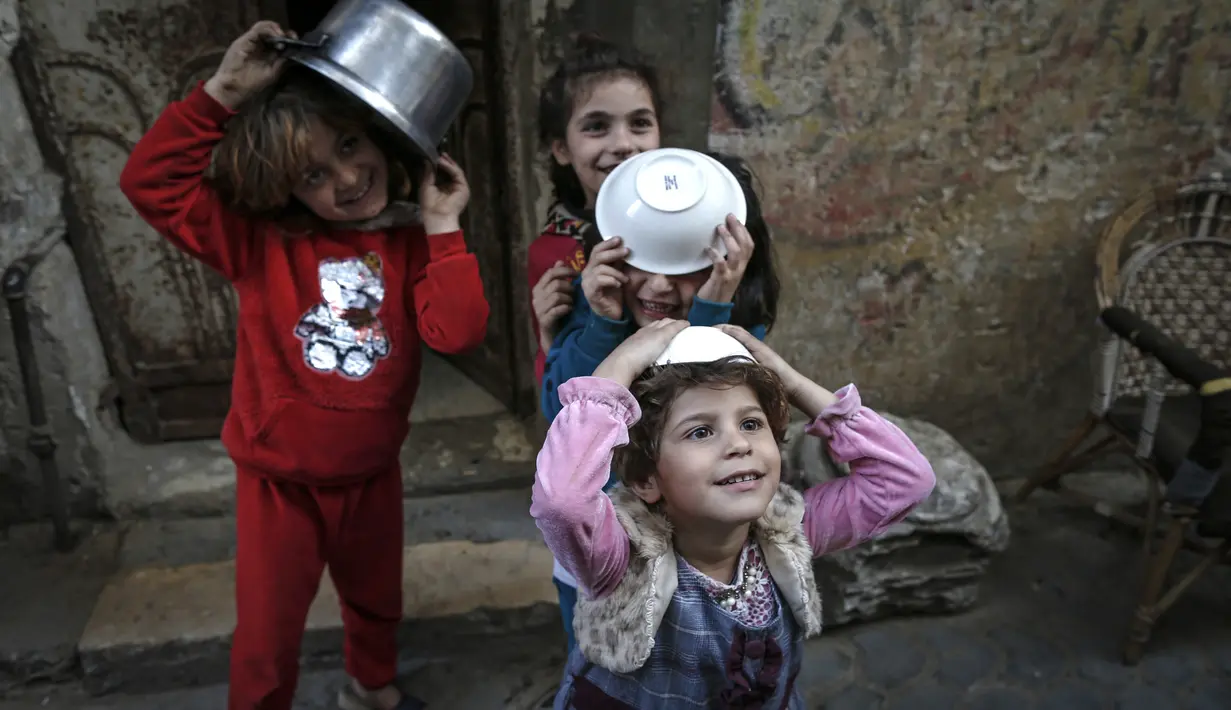 Anak-anak membawa mangkok saat Walid al-Hattab Palestina (tak terlihat) membagikan sup kepada orang-orang yang membutuhkan selama bulan puasa Ramadhan di tengah pandemi COVID-19 di Kota Gaza (14/4/2021). (AFP/Mohammed Abed)