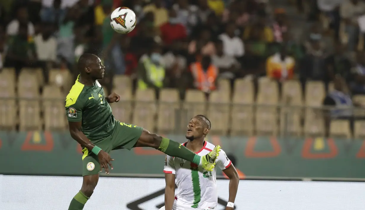 Bek Senegal, Saliou Ciss (kiri) berebut bola dengan pemain Burkina Faso, Cyrille Barros Bayala pada pertandingan semifinal Piala Afrika 2022 di stadion Ahmadou Ahidjo di Yaounde, Kamerun, Kamis (3/2/2022). Senegal menang atas Burkina Faso 3-1 dan lolos ke final. (AP Photo/Sunday Alamba)