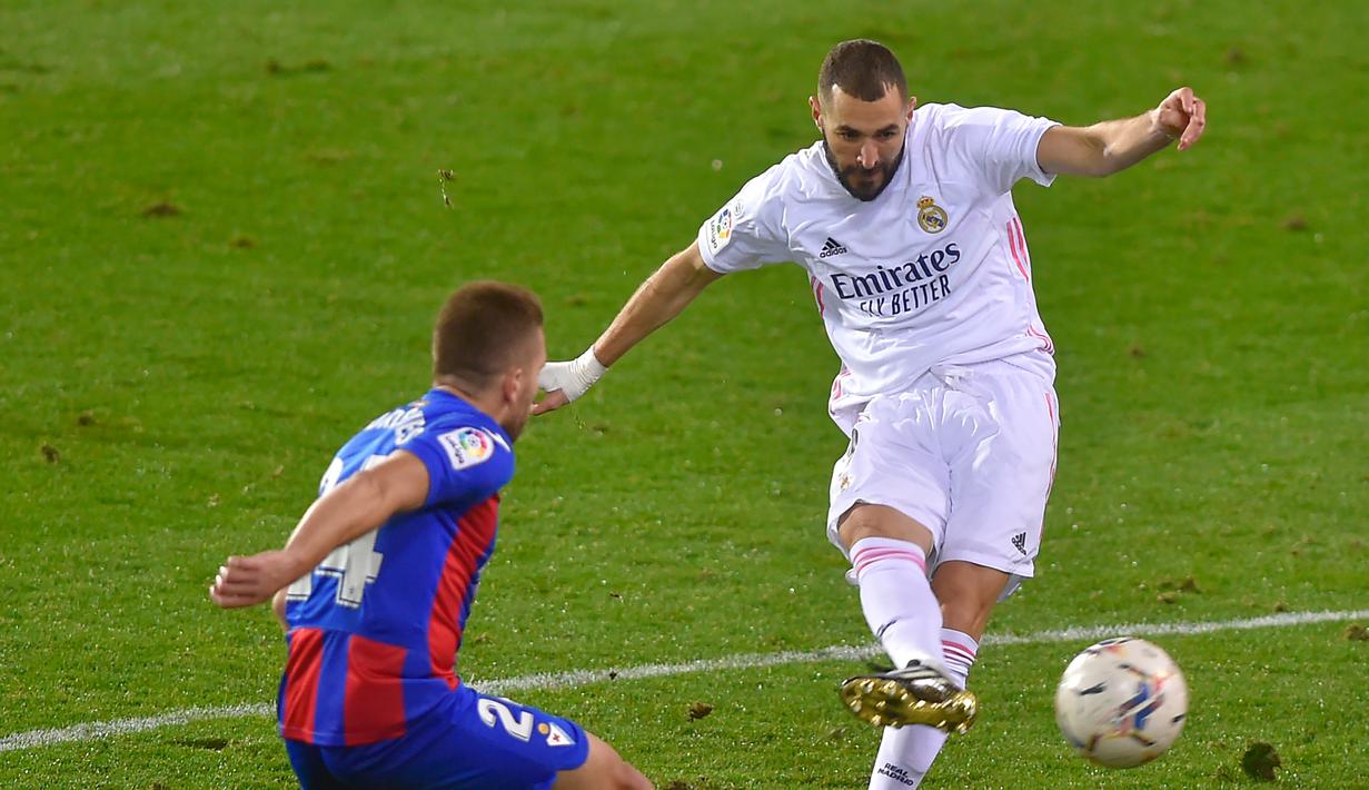 Penyerang Real Madrid Karim Benzema bersaing dengan bek Eibar Kevin Rodrigues pada laga lanjutan Liga Spanyol di Stadion Ipurua, Senin dinihari WIB (21/12/2020). Karim Benzema menjadi pahlawan dalam kemenangan Madrid karena menciptakan satu gol dan dua assist di laga tersebut. (ANDER GILLENEA/AFP)