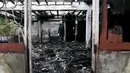 Seorang polisi memeriksa bangunan asrama sekolah yang hangus terbakar di Thailand utara, Senin (23/5). 17 siswi tewas setelah kebakaran menghanguskan asrama sekolah untuk anak-anak suku pedalaman miskin itu. (REUTERS/Athit Perawongmetha)