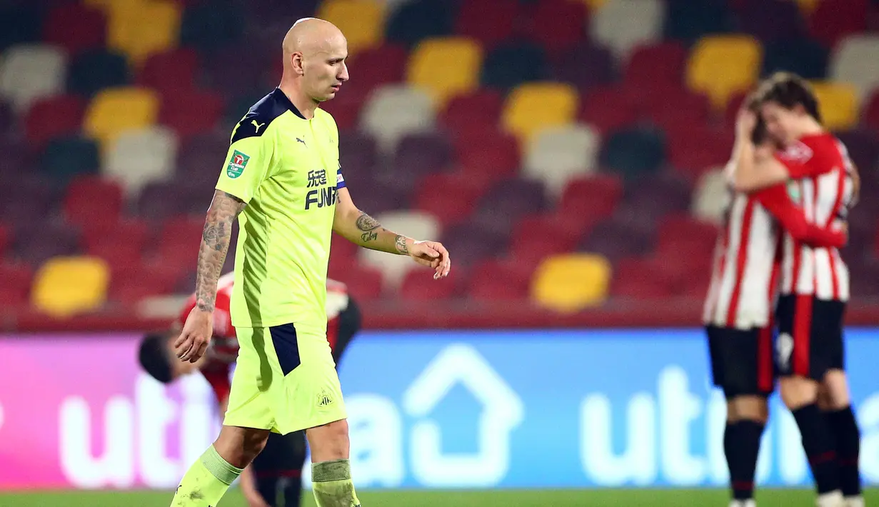 Gelandang Newcastle United, Jonjo Shelvey, meninggalkan lapangan di tengah sukacita para pemain Brentford usai berakhirnya laga perempatfinal Piala Liga Inggris Carabao Cup di Brentford Community Stadium, Selasa (22/12/2020). Newcastle United kalah 0-1 dari Brentford. (AFP/Hannah McKay/Pool)