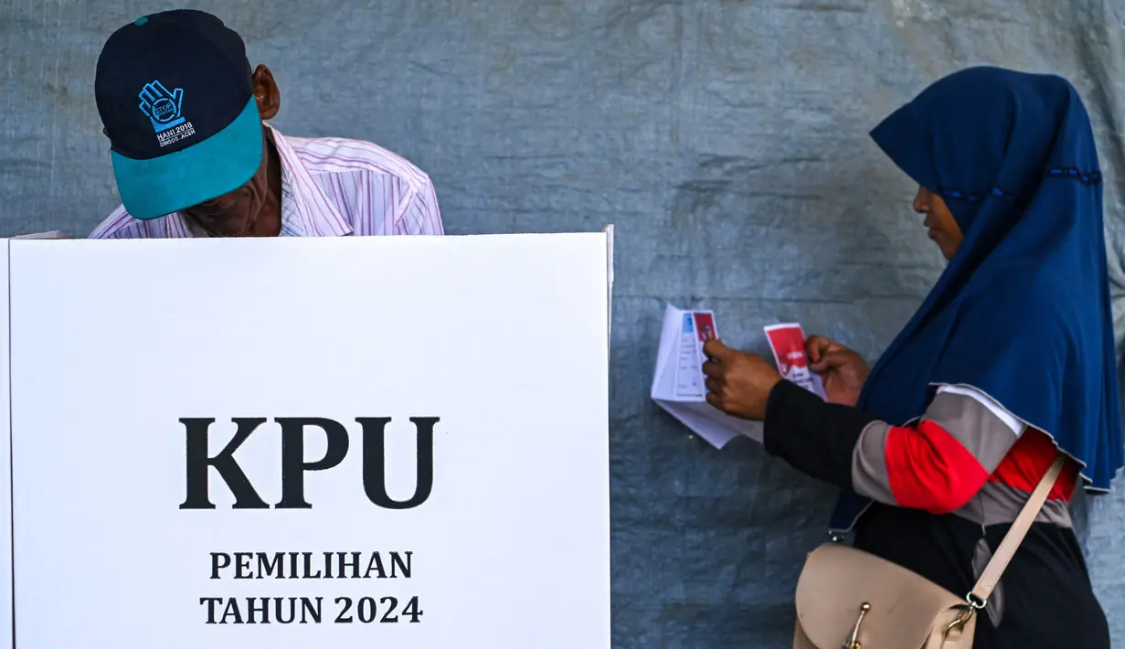 Pemilihan Kepala Daerah (Pilkada) menjadi pesta demokrasi kedua yang berlangsung di Indonesia pada tahun 2024, setelah sebelumnya, pada Februari lalu dilaksanakan Pemilihan Umum Legislatif dan Pemilihan Presiden/Wakil Presiden. Tampak dalam foto, seorang pemilih memeriksa surat suaranya sebelum memberikan suaranya dalam pemilihan kepala daerah di Darul Imarah, pinggiran Banda Aceh, pada 27 November 2024. (CHAIDEER MAHYUDDIN/AFP)