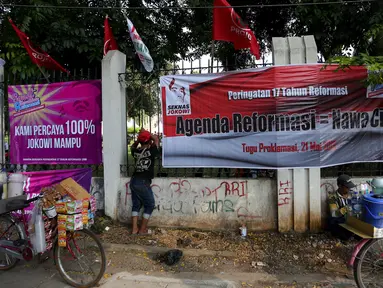 Pedagang berdiri di dekat spanduk yang berisi dukungan terhadap Jokowi, di sekitar Tugu Proklamasi, Jakarta, Kamis (21/5/2015). Spanduk tersebut dipasang dalam rangka memperingati 17 tahun reformasi. (Liputan6.com/Faizal Fanani)