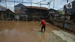 Warga membersihkan lumpur sisa banjir di Kelurahan Rawa Jati, Jakarta, Selasa (9/2/2021). Endapan lumpur yang mengendap akibat luapan Kali Ciliwung. (merdeka.com/Imam Buhori)