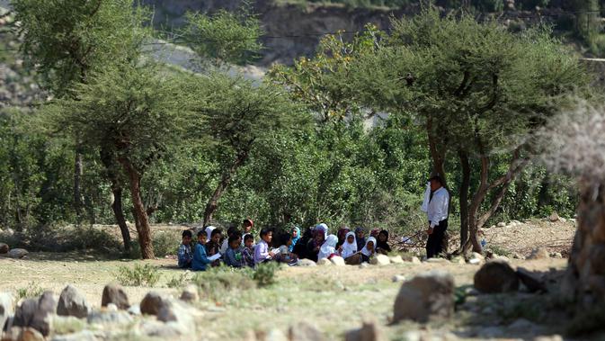 Anak-anak menghadiri kelas terbuka di bawah pohon dekat sekolah mereka yang belum selesai pada tahun ajaran baru di negara yang dilanda perang di desa al-Kashar Yaman barat daya di distrik Mashraa dan Hadnan di provinsi Taez (16/9/2019). (AFP Photo/Ahmad Al-Basha)