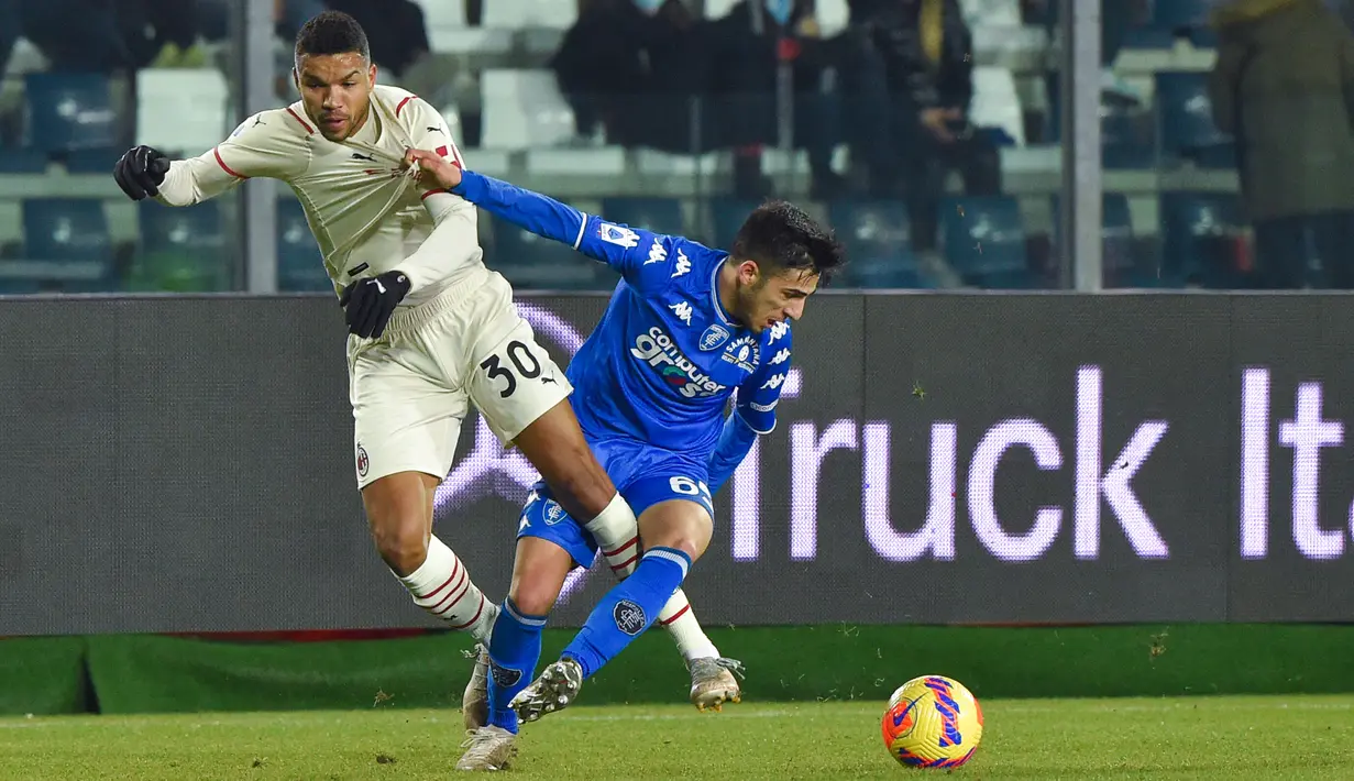 Bek Empoli, Fabiano Parisi (kanan) menahan gelandang AC Milan Junior Messias selama pertandingan Liga Serie A Italia di Stadion Carlo Castellani di Empoli, Italia, Kamis (23/12/2021). Kemenangan ini membuat AC Milan berada di posisi kedua klasemen dengan 42 poin. (AFP/Andreas Solaro)