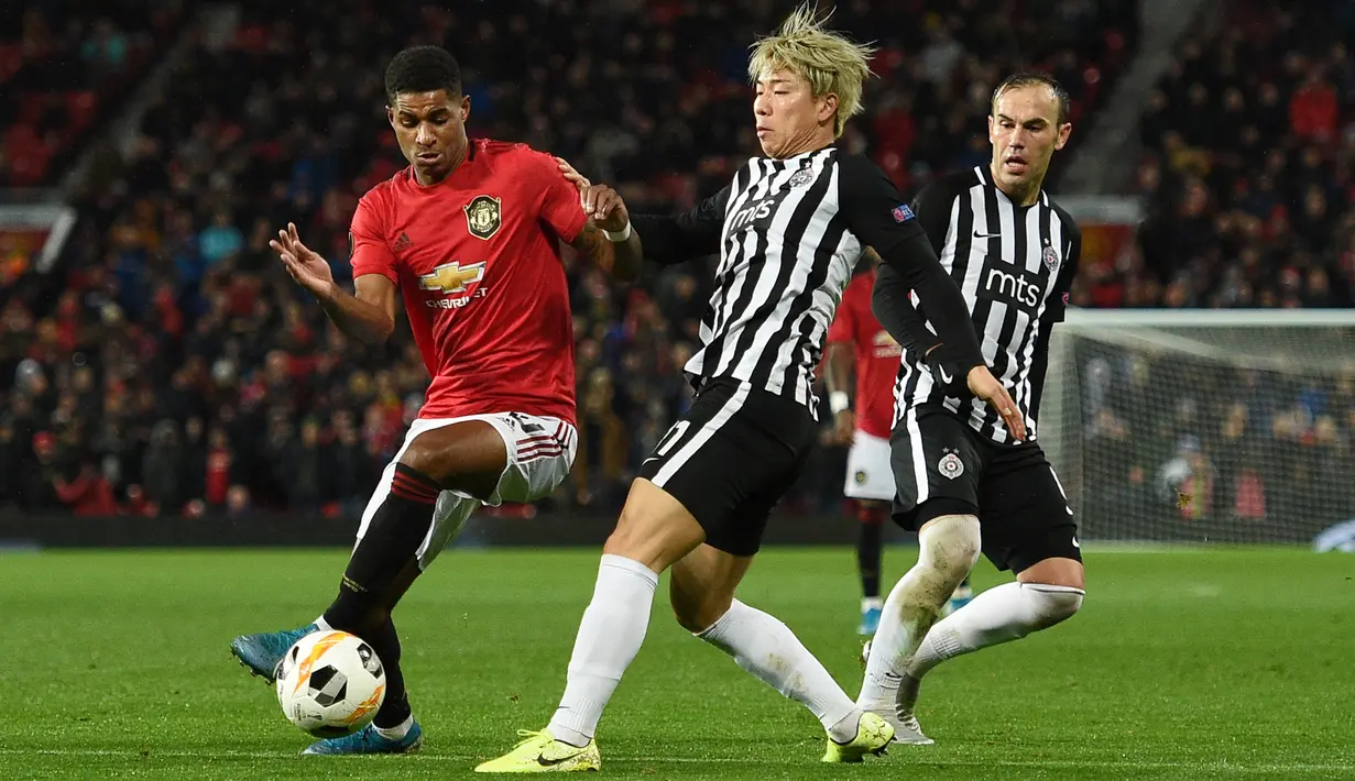Penyerang Manchester United (MU) Marcus Rashford berebut bola dengan pemain Partizan, Takuma Asano pada matchday keempat Grup L Liga Europa di Old Trafford, Kamis (7/11/2019). Tampil di hadapan pendukungnya sendiri, MU mengalahkan Partizan Belgrade 3-0. (Oli SCARFF / AFP)