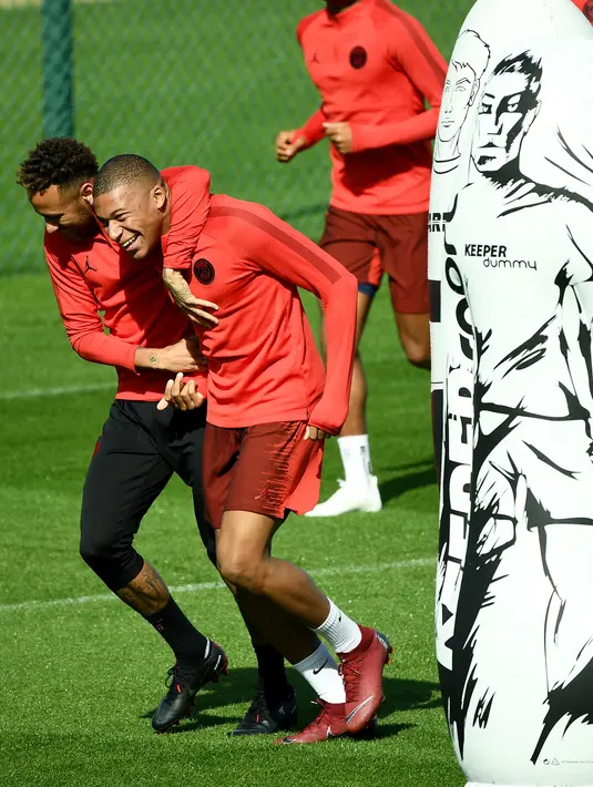 Pemain Paris Saint-Germain (PSG), Neymar (kiri) merangkul Kylian Mbappe (kanan) saat sesi latihan di Paris Barat, Prancis, Senin (17/9). PSG akan menghadapi Liverpool di Liga Champions pada 19 September 2018. (FRANCK FIFE/AFP)