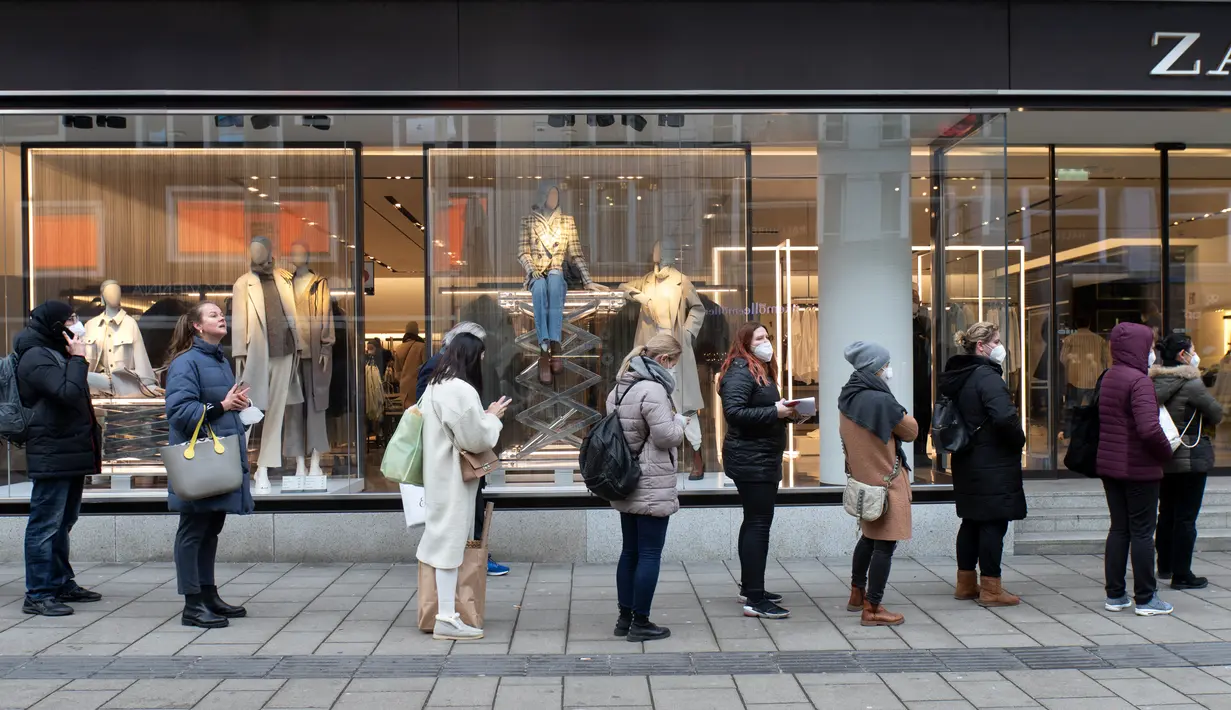 Orang-orang dengan masker FFP2 menunggu di depan toko yang masih tutup di shopping streetterkenal Mariahilferstrasse di Wina, Senin (8/2/2021). Austria mulai melonggarkan lockdown covid-19 ketiga mereka mulai 8 Februari dengan mengizinkan sekolah, museum dan toko dibuka kembali. (ALEX HALADA/AFP)