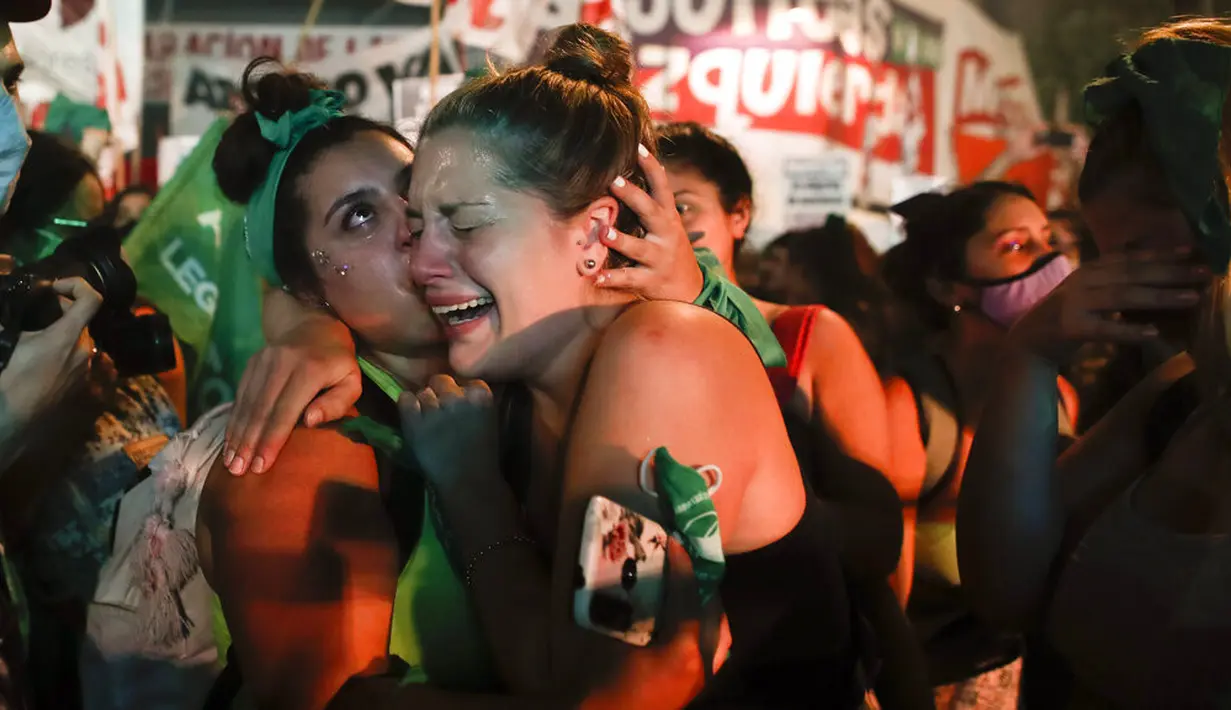 Aktivis hak-hak aborsi menangis sambil berpelukan setelah anggota parlemen menyetujui undang-undang yang melegalkan aborsi di luar Kongres, Buenos Aires, Argentina, Rabu (30/12/2020). Kongres Argentina menyetujui undang-undang yang melegalkan aborsi. (AP Photo/Natacha Pisarenko)