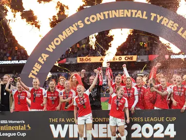 Bek Arsenal, Leah Williamson (tengah kiri) dan Kim Little memegang trofi saat merayakan kemenangan setelah final Piala Liga Wanita Inggris di Molineux, Wolverhampton, Inggris pada 31 Maret 2024. (Adrian DENNIS/AFP)