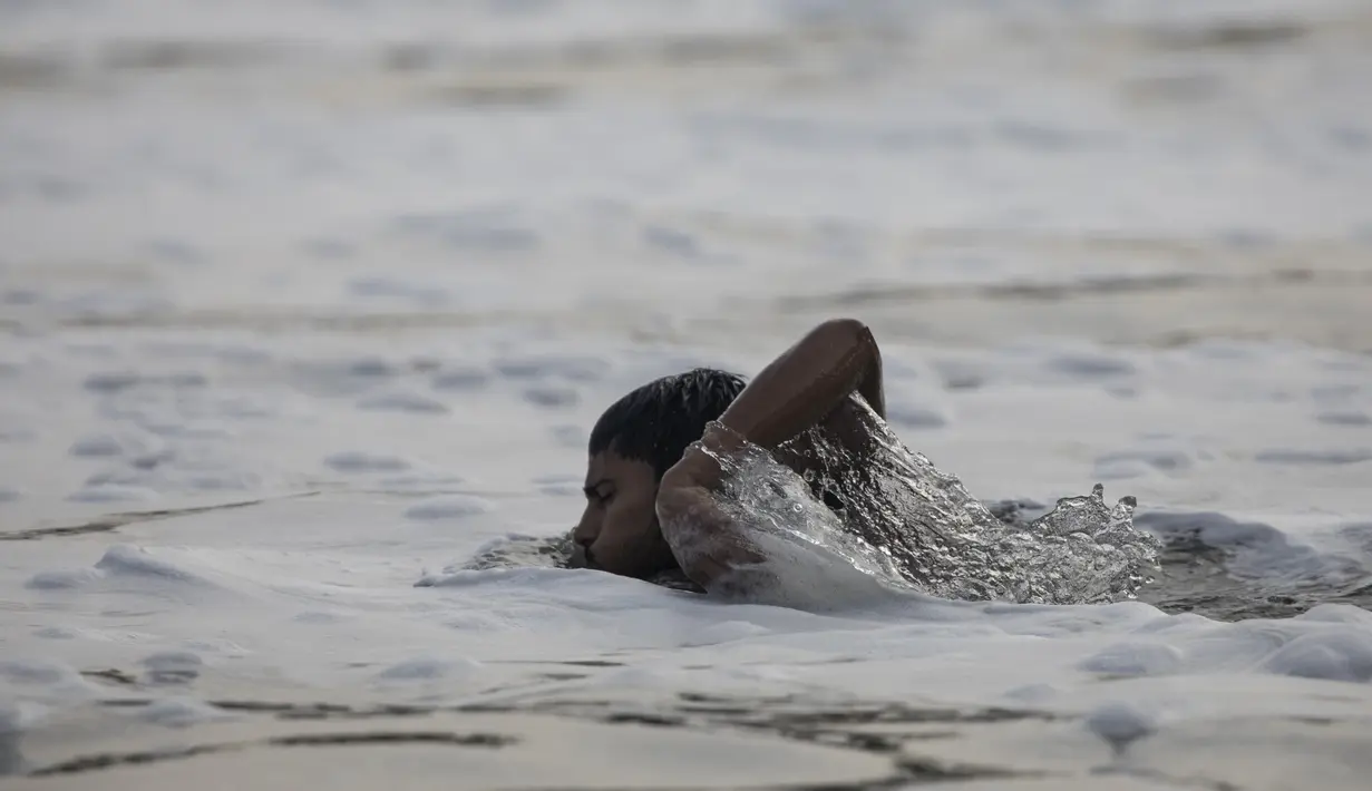 Seorang pemuda berenang di tengah busa di sungai Yamuna yang tercemar di pinggiran New Delhi (23/7/2020). Sungai yang sangat dianggap suci oleh umat Hindu India ini masih tercemar, salah satunya akibat busa polusi memenuhinya. (AFP Photo/Xavier Galiana)