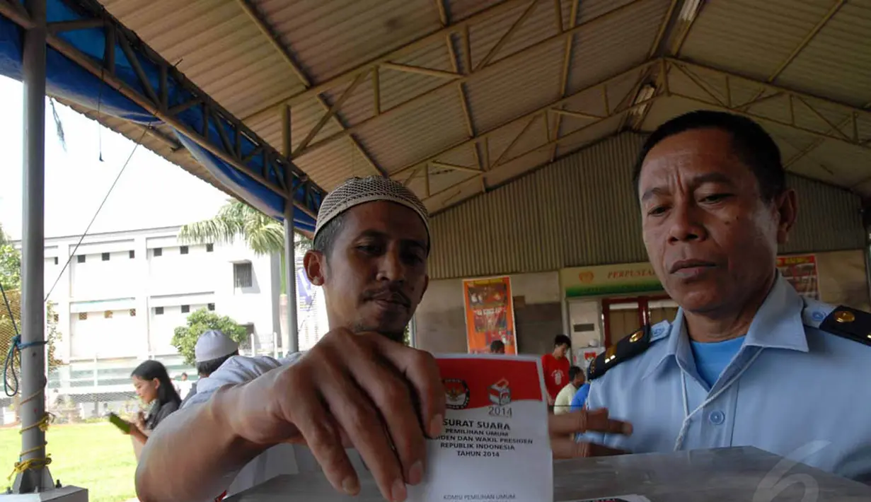 Petugas LP Cipinang tampak mendampingi seorang napi yang memasukkan kertas ke dalam kotak suara (Liputan6.com/ Miftahul Hayat).