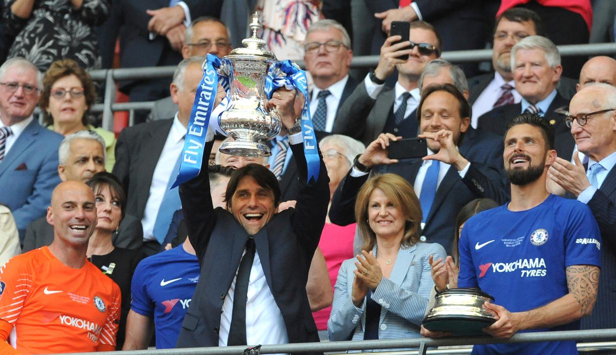 Pelatih Chelsea, Antonio Conte mengangkat trofi Piala FA usai pertandingan melawan Manchester United pada babak final Piala FA di stadion Wembley di London (19/5). Chelsea mengalahkan MU 1-0. (AP Photo / Tim Ireland)