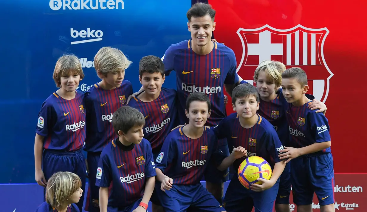Gelandang baru Barcelona, Philippe Coutinho foto bersama dengan anak-anak saat perkenalan dirinya di Nou Camp, Barcelona (8/1). Coutinho diboyong Barcelona dengan harga sebesar 400 juta euro (sekitar Rp 6,45 triliun). (AFP Photo/Lluis Gene)