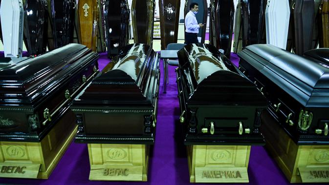 Seorang pria berjalan di antara peti mati selama pameran pemakaman di Moskow, Rusia pada Rabu (21/10/2020). (Photo by Kirill KUDRYAVTSEV / AFP)