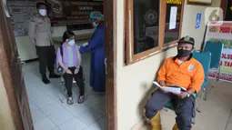 Seorang pria (kanan) menunggu untuk menerima vaksin covid-19 di Polsek Pamulang, Tangsel, Kamis (1/7/2021). Sebanyak 10 ribu dosis vaksin untuk warga 18 tahun ke atas dibagikan di wilayah Polres Tangerang Selatan dalam rangka HUT Bhayangkara Ke-75 yang jatuh pada hari ini. (merdeka.com/Arie Basuki)