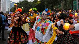 Peserta yang berdandan ala tengkorak menari saat mengikuti parade Hari Orang Mati di Mexico City, Meksiko, Sabtu (26/10/2019. Para peserta dalam parade ini mengenakan kostum dan melukis wajah mirip dengan tokoh tengkorak Meksiko yang ikonik, Catrina. (AP Photo/Ginnette Riquelme)