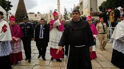 Uskup Agung Pierbattista Pizzaballa menyapa jemaatnya saat mengikuti sebuah prosesi di Manger Square di luar Gereja Nativity di Kota Betlehem, Palestina, Minggu (24/12). (AFP/Musa Al Shaer)