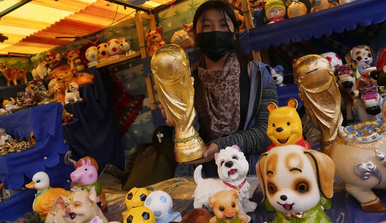 Penjual menjual replika trofi Piala Dunia pada hari pembukaan Alasita Fair tahunan di El Alto, Bolivia, Selasa (24/1/2023). Orang-orang membeli replika kecil dari hal-hal yang ingin mereka peroleh sepanjang tahun, seperti rumah, mobil, dan kekayaan. Kata Aymara "Alasita" berarti "belikan aku". (AP Photo/Juan Karita)