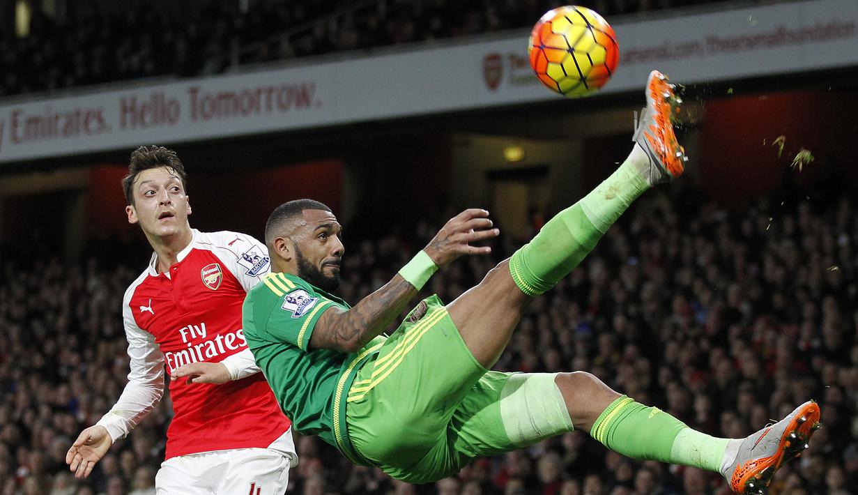 Pemain Arsenal, Mesut Ozil (kiri) melihat pemain Sunderland, Yann M'vila melakukan tendangan salto pada lanjutan Liga  Premier Inggris di Stadion Emirates, London, Sabtu (5/12/2015). (AFP Photo/Ikimages) 