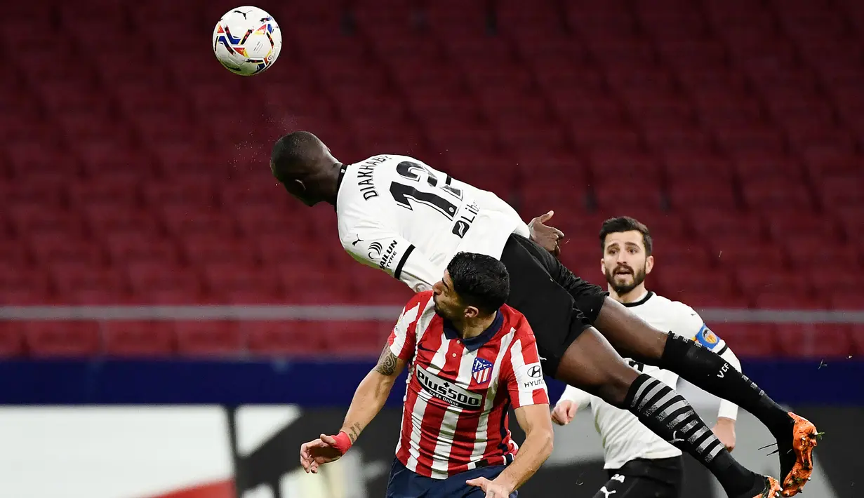 Striker Atletico Madrid, Luis Suarez, duel udara dengan pemain Valencia, Mouctar Diakhaby, pada laga Liga Spanyol di Stadion Wanda Metropolitano, Minggu (24/1/2021). Atletico Madrid menang dengan skor 3-1. (AFP/Pierre Philippe Marcou)
