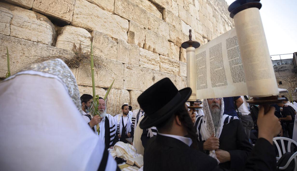 Pria Yahudi Ultra-Ortodoks berdoa selama hari raya Yahudi Sukkot di Tembok Barat, situs paling suci di mana orang Yahudi dapat berdoa di Kota Tua Yerusalem, Rabu (22/9/2021).  (AP Photo/Sebastian Scheiner)