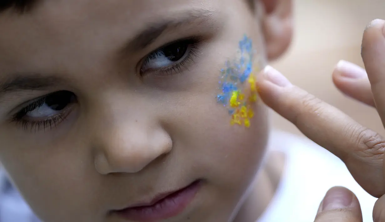 Seorang anak laki-laki didandani dengan warna nasional Ukraina untuk perayaan hari Kemerdekaan Ukraina di Chichester, Inggris selatan, Sabtu, 27 Agustus 2022. Chichester dinobatkan sebagai daerah paling dermawan di negara itu untuk menampung pengungsi Ukraina. (AP Photo/Frank Augstein)