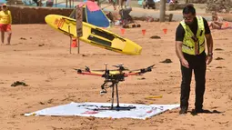 Ben Trollope bersiap menerbangkan drone pendeteksi hiu di Pantai Bilgola, utara Sydney, Australia, 10 Desember 2017. Drone ini dilengkapi megafon untuk memberi peringatan kepada perenang dan orang sekitar pantai tentang kehadiran hiu. (PETER PARKS/AFP)