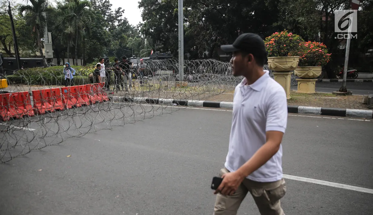 Seorang pria melintas di depan kawat berduri yang dipasang di Kedutaan Besar Myanmar, Jakarta, Rabu (6/9).  (Liputan6.com/Faizal Fanani)