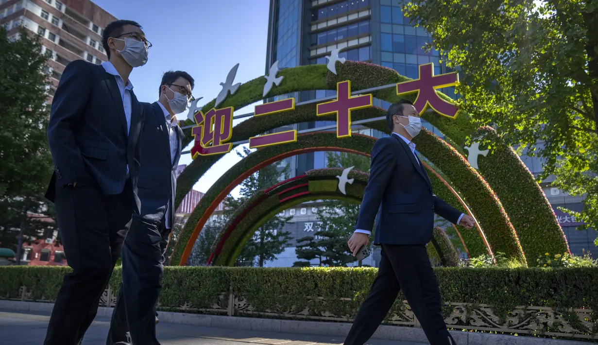 Orang-orang berjalan melewati pajangan yang menandai Kongres Nasional ke-20 Partai Komunis China yang akan datang, di Beijing, Selasa (11/10/2022). Para pemimpin tidak ingin wabah besar merusak kongres, tetapi pendekatan ketat "nol-Covid" mereka telah merugikan ekonomi, terutama pada usaha kecil dan pekerja sementara. (AP Photo/Mark Schiefelbein)
