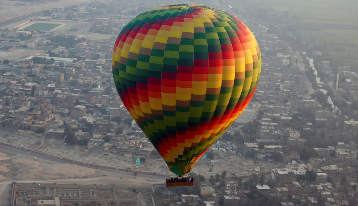 Balon udara panas terbang membawa wisatawan mengudara di atas kota Luxor, Kairo, Mesir (13/12). Wisatawan akan menikmati pemandangan situs-situs kuno di kota Luxor dari atas balon udara panas.  (Reuters/Amr Abdallah Dalsh)