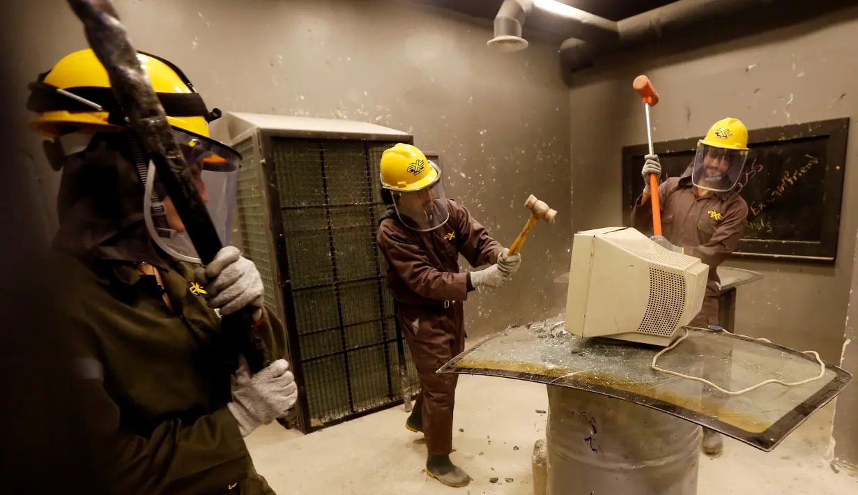 Warga Yordania menghancurkan sebuah komputer dengan palu saat melampiaskan kemarahannya di AXE Rage Room di Amman, Yordania (17/4). Pelampiasan ini hanya untuk menghibur bagi mereka yang memiliki amarah yang terpendam. (Reuters/Muhammad Hamed)