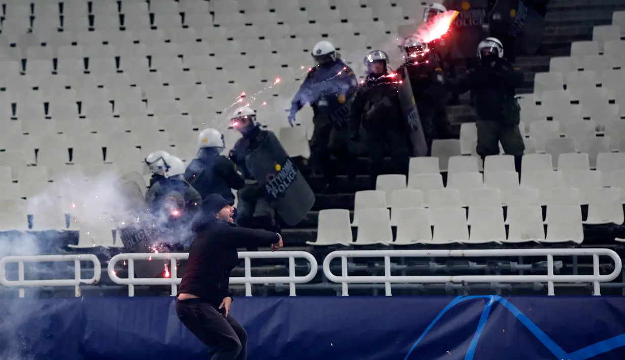Seorang suporter melempar flare ke arah pendukung Ajax sebelum pertandingan Liga Champions melawan AEK Athena di Stadion Olimpiade Athena, Selasa (27/11). Suporter tuan rumah melakukan aksi brutal ke arah tribun suporter Ajax. (AP/Thanassis Stavrakis)