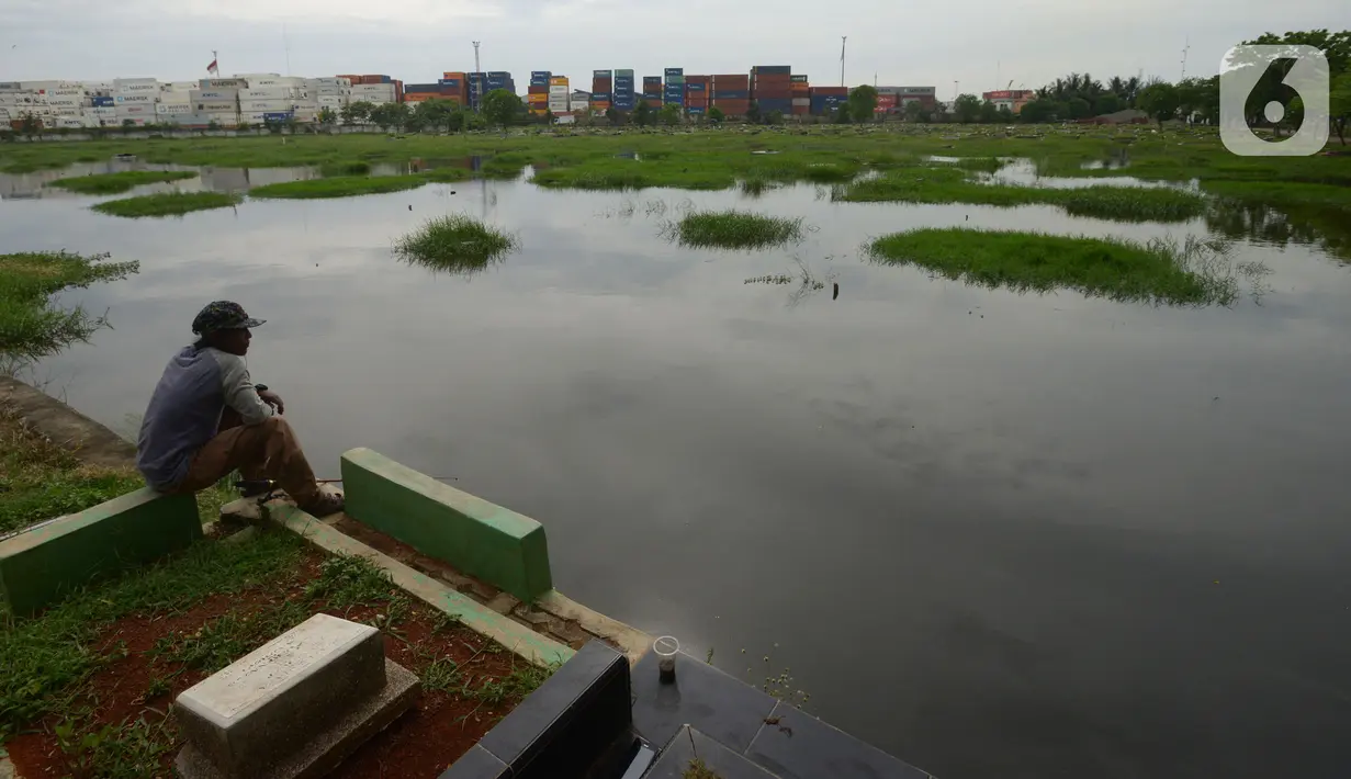 Warga memancing ikan di Tempat Pemakaman Umum (TPU) Semper yang terendam banjir, Jakarta, Kamis (11/11/2021). Ratusan makan di TPU Semper terendam banjir akibat hujan deras yang menguyur Ibu Kota beberapa hari lalu. (merdeka.com/Imam Buhori)