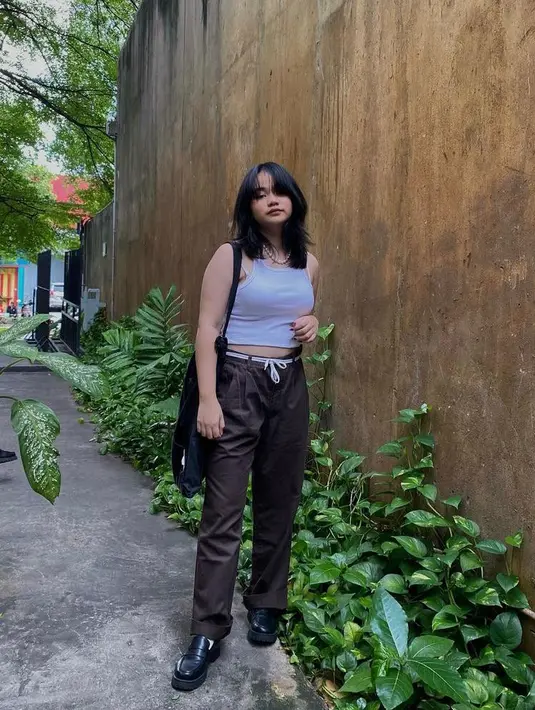 Simple tapi chic, kali ini Mima tampil memadukan sleeveless crop top warna putih, high waist pants warna coklat, totebag dan sepatu kulit warna hitam. (Instagram/mimashafa).