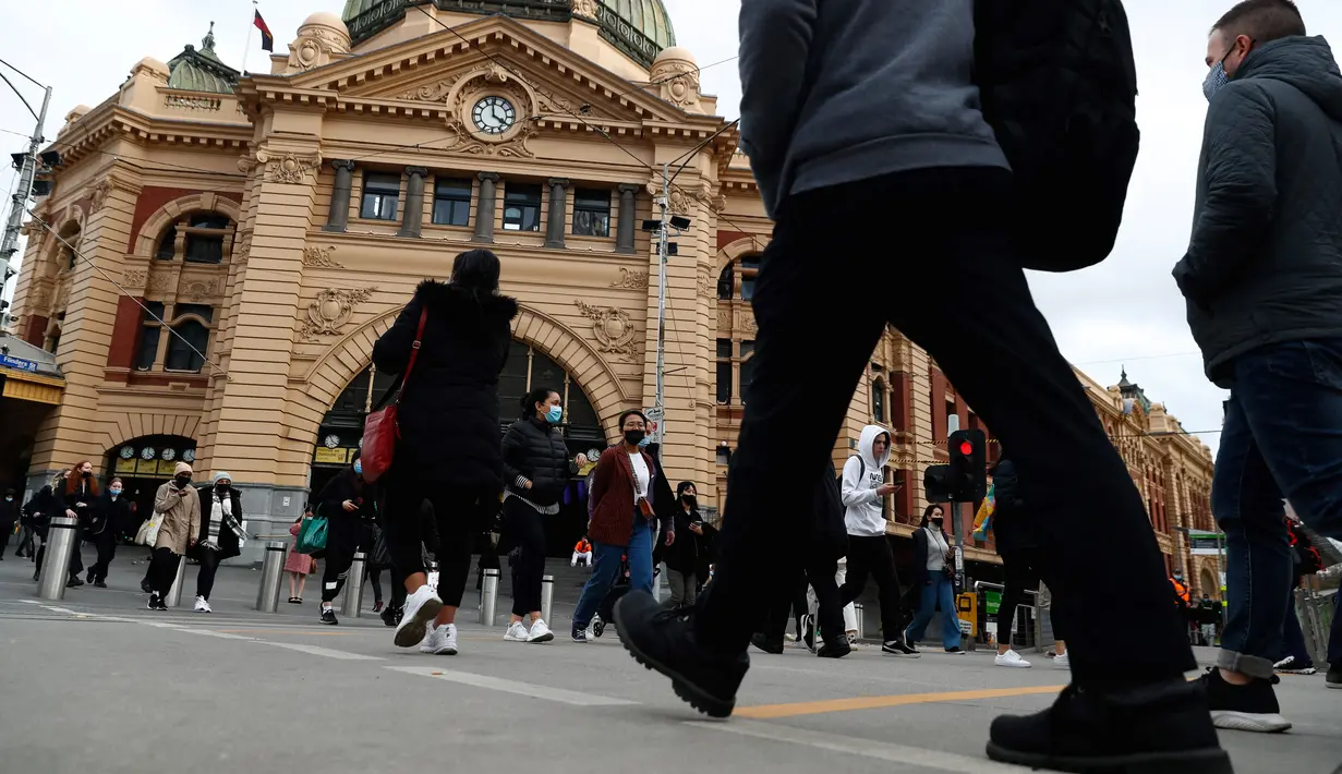 Orang-orang berjalan di luar Stasiun Flinders Street di pusat kota Melbourne ketika pihak berwenang mengumumkan lockdown untuk keenam kalinya di kota itu, pada Kamis (5/8/2021).  Lockdown di kota terpadat kedua di Australia tersebut guna mengendalikan penyebaran Covid varian delta. (Con Chronis/AFP)