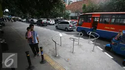 Pejalan kaki melintas di samping Portal S Ramah Disabilitas di trotoar RSCM, Jakarta, Jumat (26/8). Selain ramah disabilitas dan Lansia, portal tersebut juga berfungsi untuk mencegah sepeda motor masuk ke jalur trotoar. (Liputan6.com/Immanuel Antonius)