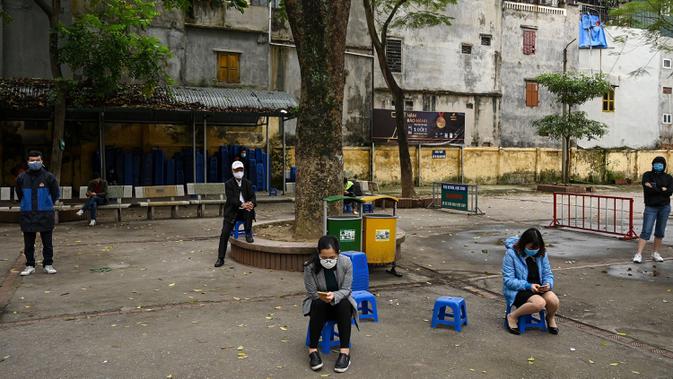 Penduduk memakai masker mengantre dengan tertib saat akan mengikuti pengujian Covid-19 di pusat pengujian dekat rumah sakit Bach Ma, Hanoi, Vietnam (31/3/2020). Warga Vietnam antusias mengikuti tes Covid-19 dengan tertib di tengah masifnya penyebaran Covid-19 di dunia. (AFP/Manan Vatsyayana)