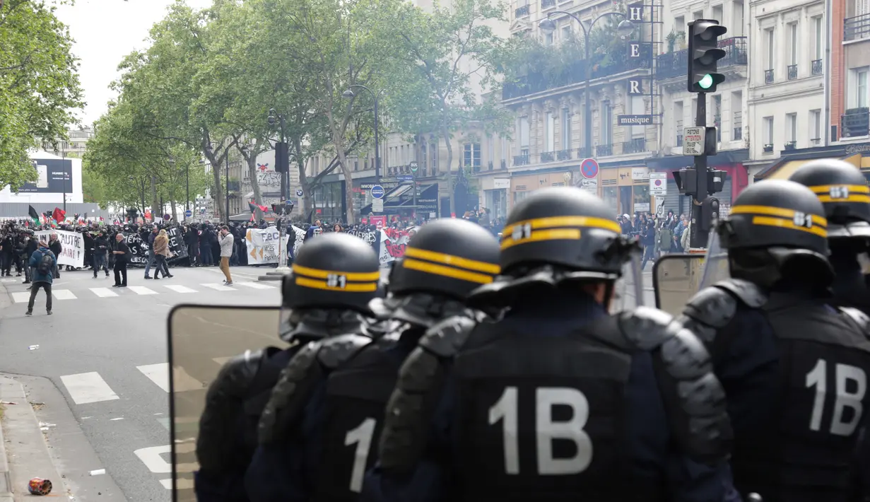 Polisi anti huru-hara Prancis menghadapi pengunjuk rasa perayaan May Day di Paris, Senin (1/5). Seorang perwira polisi mengalami luka bakar serius dan dua lainnya luka-luka dalam bentrokan yang melibatkan bom molotov tersebut. (Zakaria ABDELKAFI/AFP)