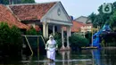 Siswi berjalan melewati banjir yang menggenangi halaman  sekolah di SMAN 4 Tangsel, Pondok Ranji, Tangerang Selatan, Banten, Selasa (14/6/2022). Tiga  pekan lebih banjir merendam lapangan sekolah itu dikarenakan tertutupnya saluran air oleh sampah yang berasal dari tempat pembuangan sampah (TPS) ilegal. (merdeka.com/Arie Basuki)