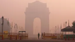 Petugas keamanan berjaga di depan India Gate yang diselimuti kabut tebal di New Delhi, India (31/10). Kabut tebal polusi ini menimbulkan kekhawatiran resiko berbagai penyakit yang berdampak pada penduduk kota New Delhi. (Reuters/Adnan Abidi)