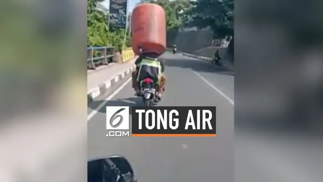 Seorang pria memakai tong air diatas kepalanya saat mengendarai sepeda motor.