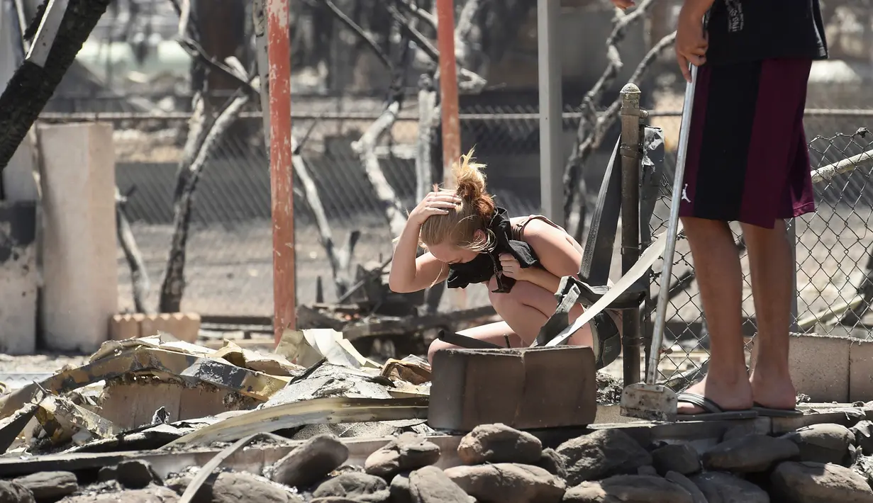 Seorang wanita menangis saat menemukan hewan peliharaannya tewas akibat kebakaran dahsyat di sepanjang South Lake, California, AS (24/6). (REUTERS/Noah Berger)