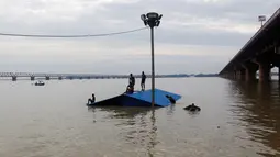 Warga memanjat atap rumah saat terjebak banjir di Allahabad, India (21/8). Banjir bandang menerjang sejumlah wilayah di India yang menyebabkan banyak warga yang terjebak. (REUTERS/Jitendra Prakash)